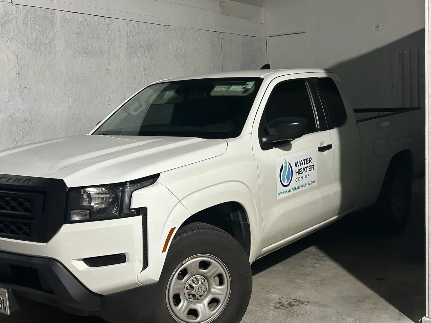 A white Water Heater Genius service truck with the company logo and website on the driver’s door.